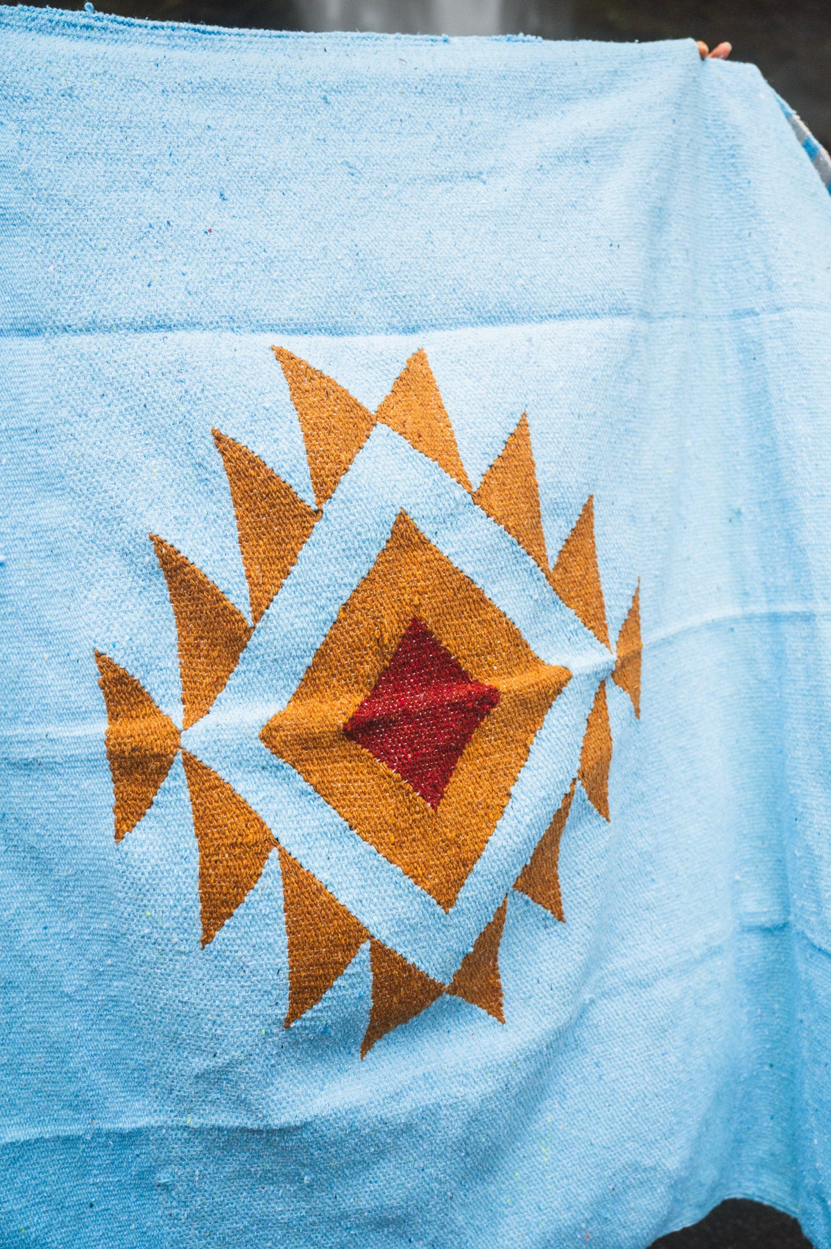 Blue fabric with a geometric pattern featuring orange and red colors.