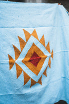 Blue fabric with a geometric pattern featuring orange and red colors.