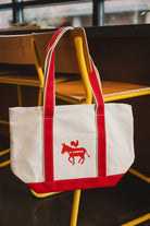 Red and white tote bag with a logo on a chair