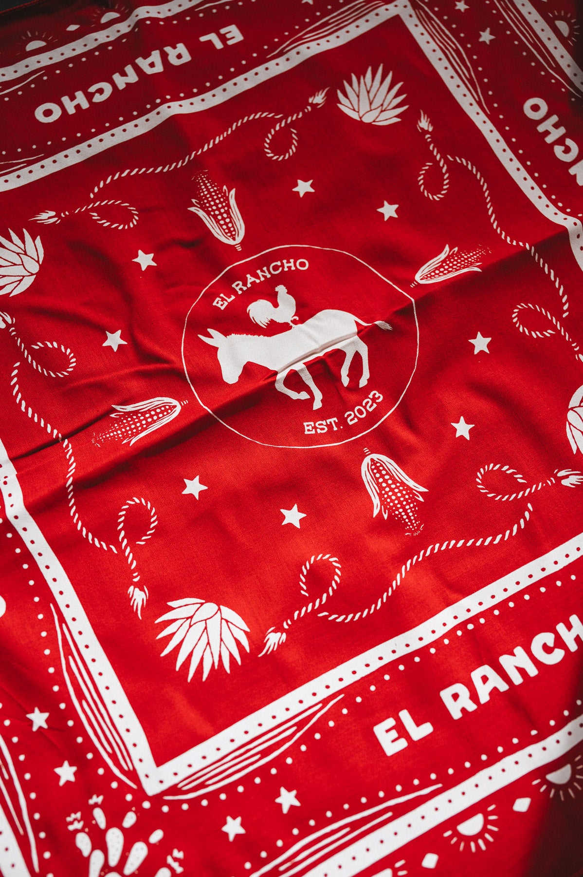 Red bandana with white patterns and 'El Rancho' branding
