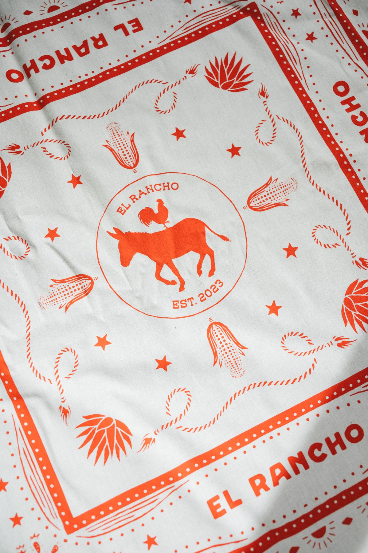White fabric with red 'El Rancho' branding and illustrations