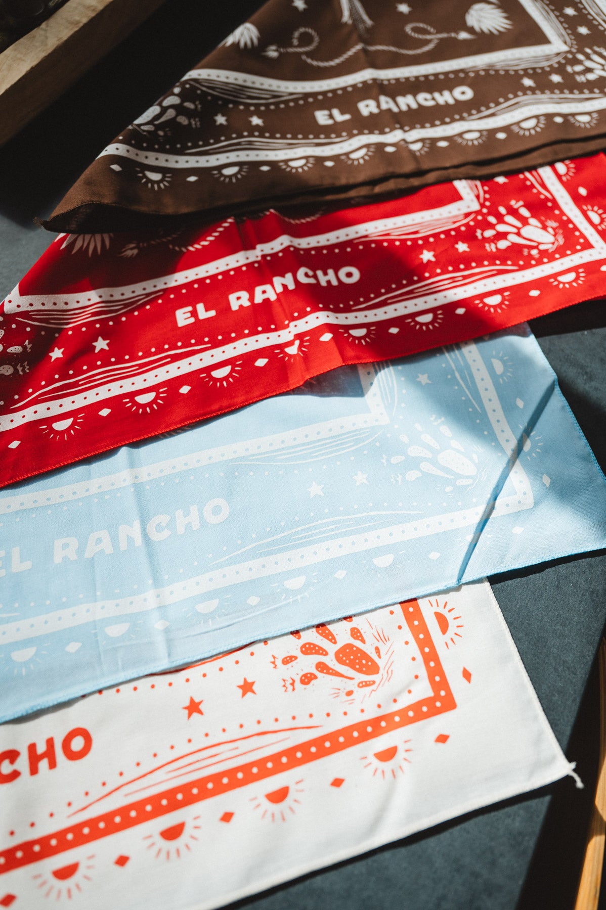 Collection of bandanas with 'El Rancho' branding on a flat surface