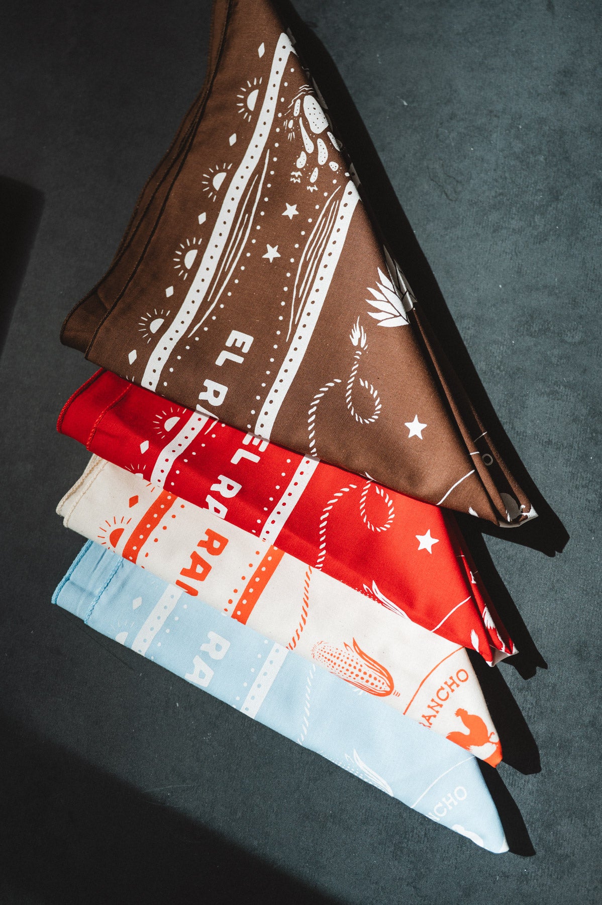 Stack of bandanas with different patterns and colors on a dark surface