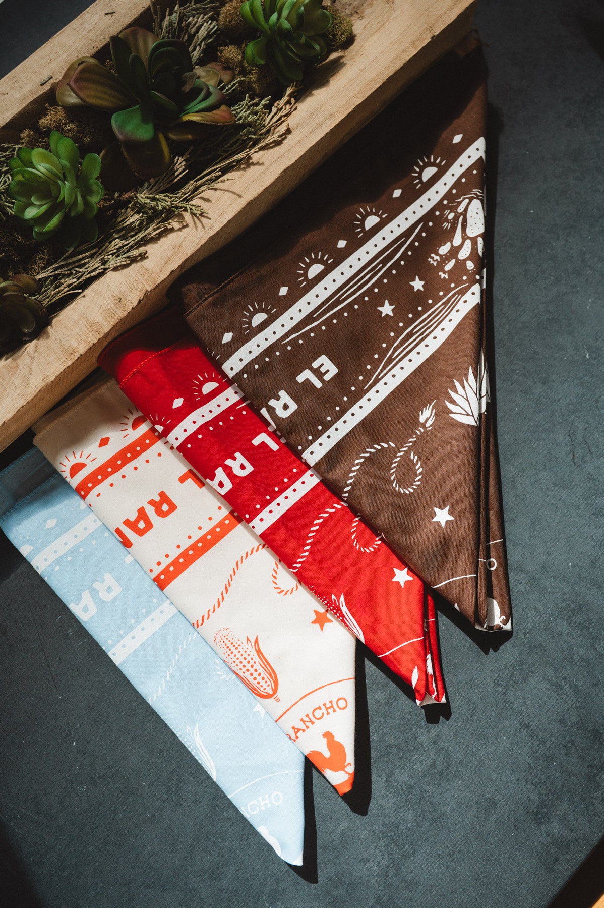 Two fabric swatches, one red and white patterned and one brown with white designs, on a dark surface.