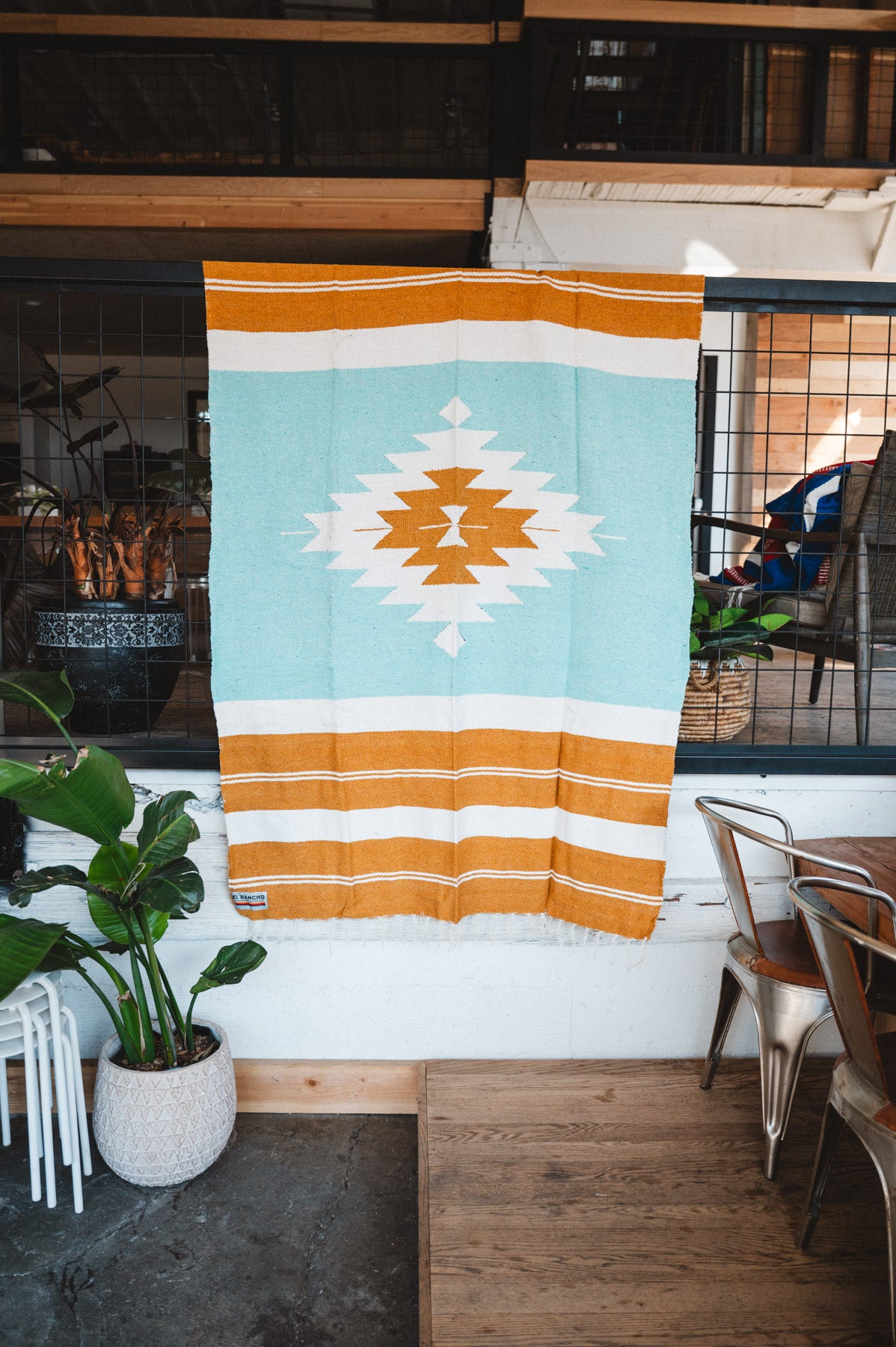 andwoven Mexican Blanket Turquoise and gold color Diamond pattern in modern industrial setting