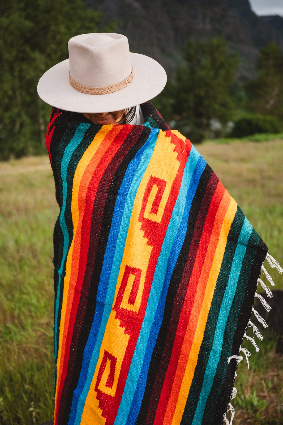 Mexican woman wrapped in a multicolored handwoven mexican blanket with greca designs