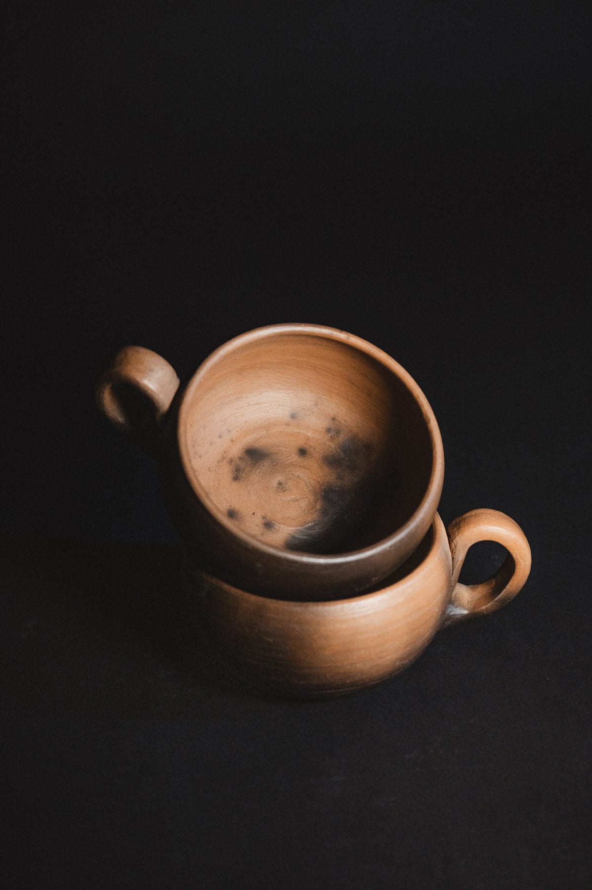 Two stacked ceramic cups on a dark background
