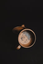 Ceramic mug with a dark interior on a black background