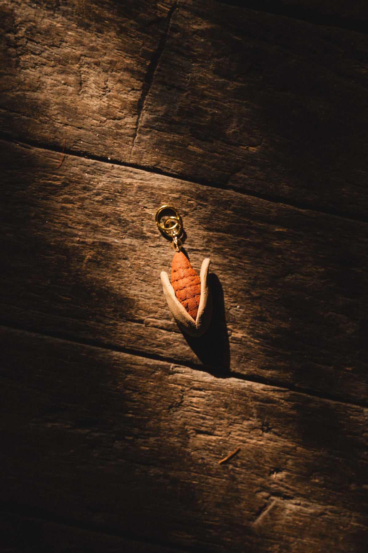 handmade clay elote pendant on wood floor