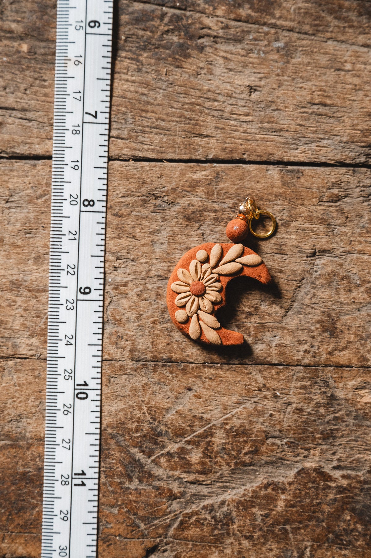 Handmade Filigrana Oaxacan Moon Pendant on wood background with measuring tape