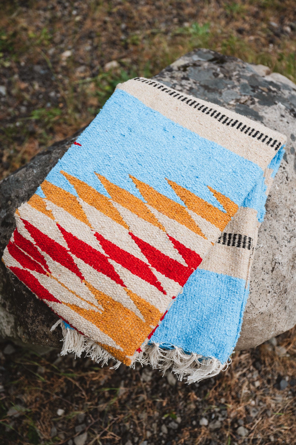 Folded blue and gold mexican blanket sitting on a rock