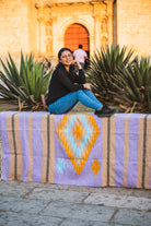 Santo Domingo Church Oaxaca and a girl sitting on a handwoven mexican blanket in front of it