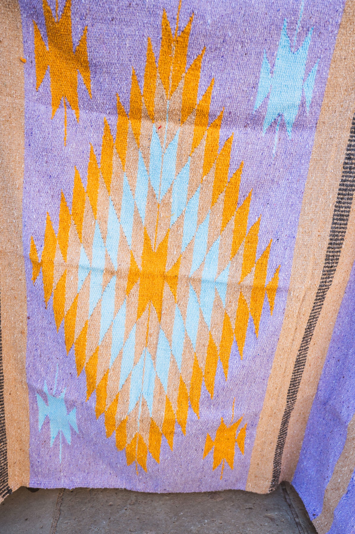 Textile with geometric pattern featuring orange and blue diamonds on a purple background