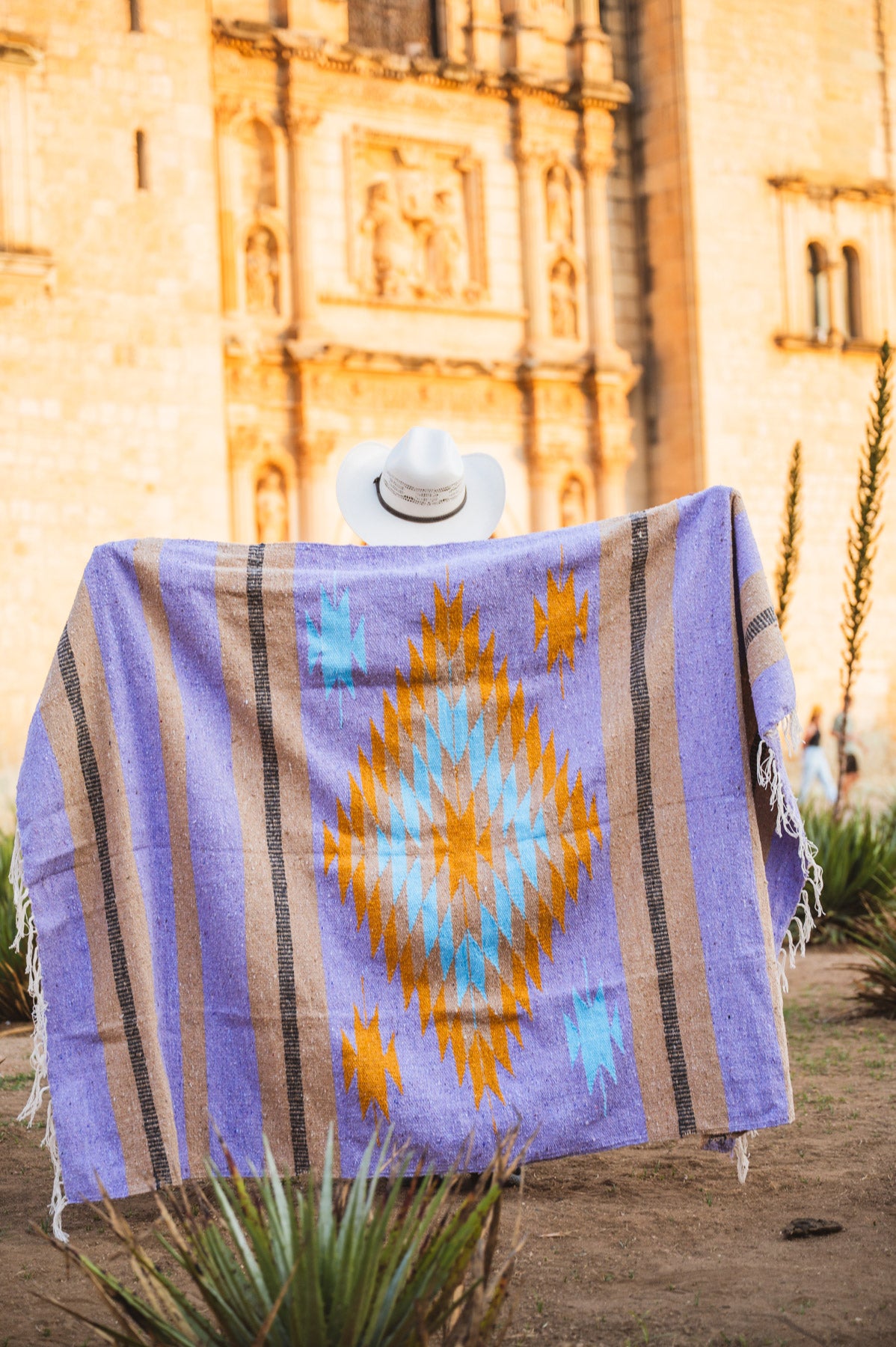 Santo Domingo Church Oaxaca and a girl standing with a handwoven mexican blanket in front of it