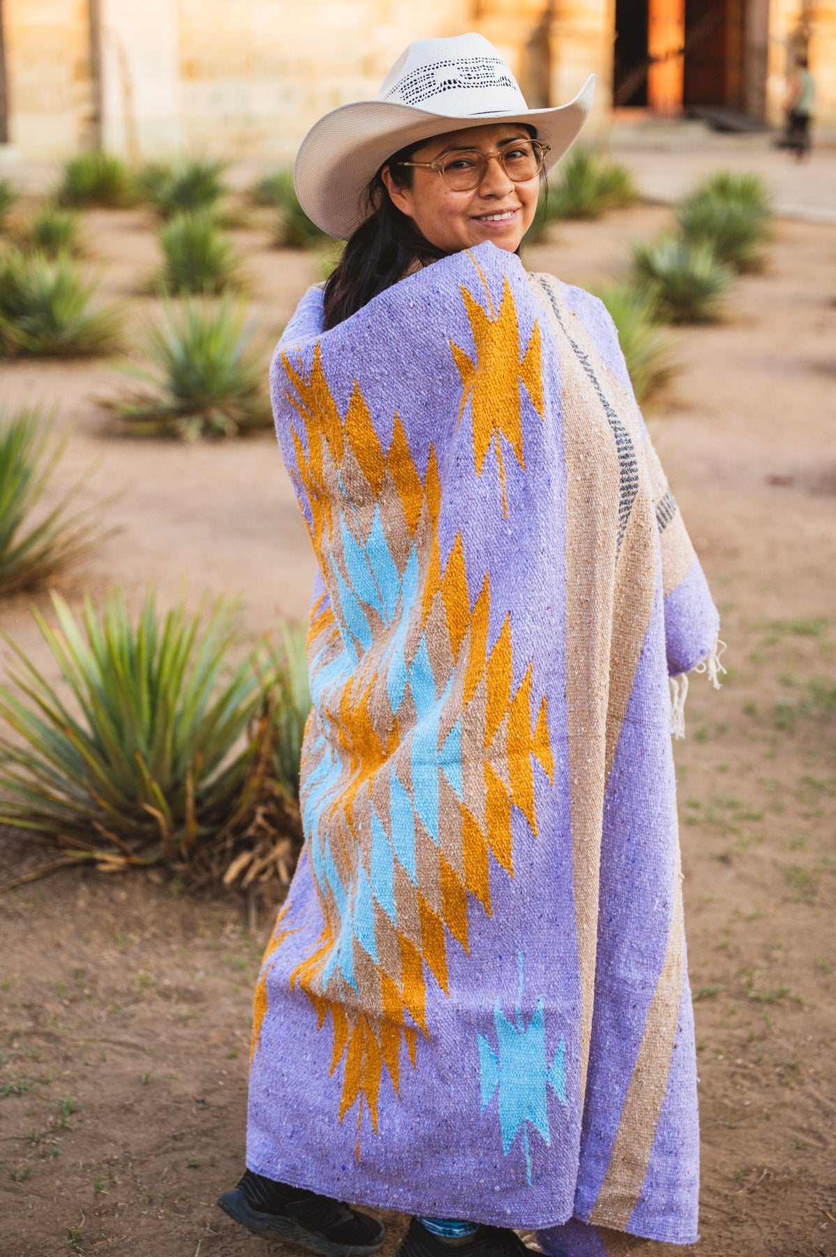 Santo Domingo Church Oaxaca and a girl standing with  a handwoven mexican blanket in front of it