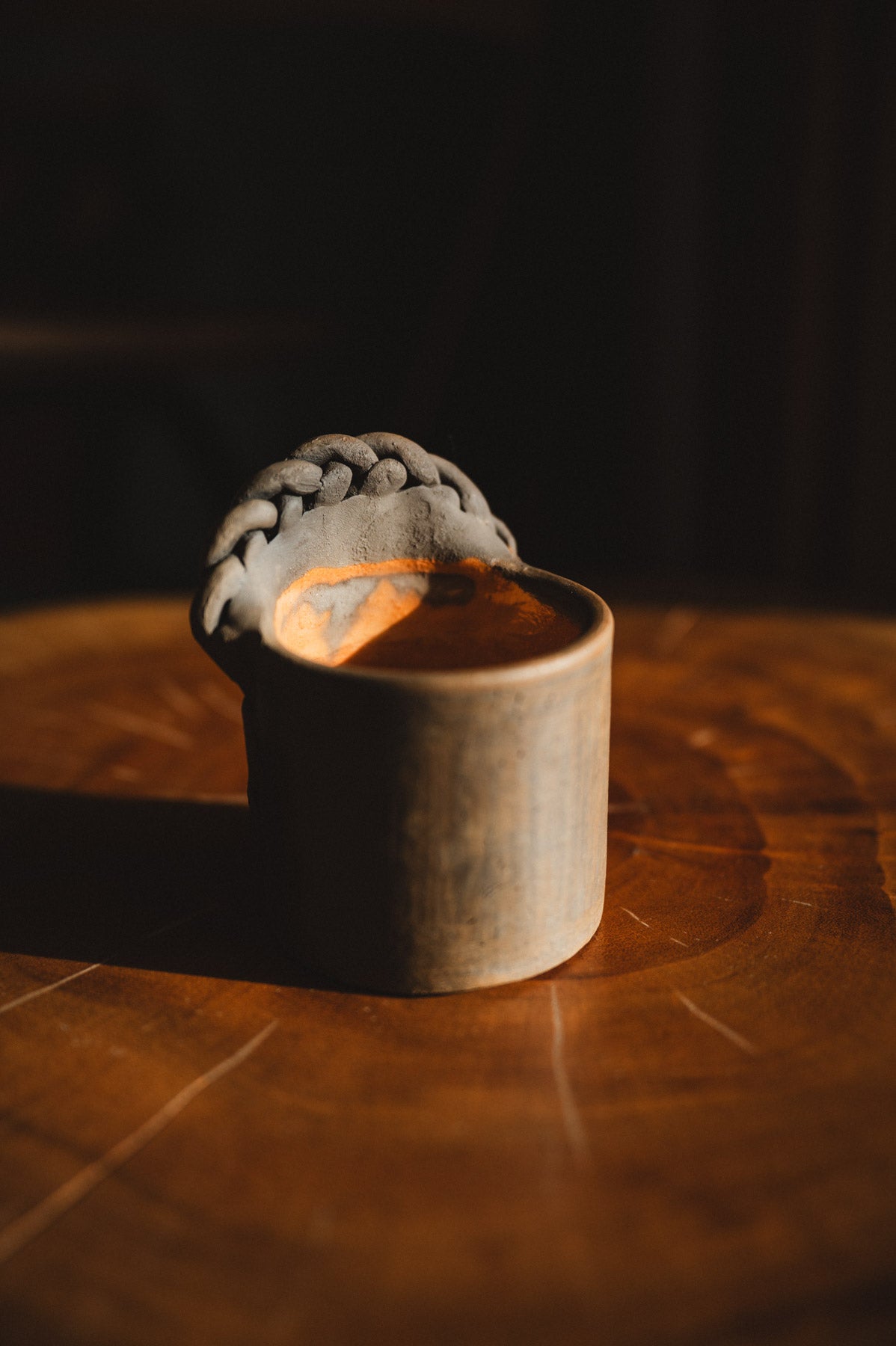 Small wooden cup with a gray woven object on a dark background