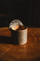 Small wooden cup with a gray woven object on a dark background