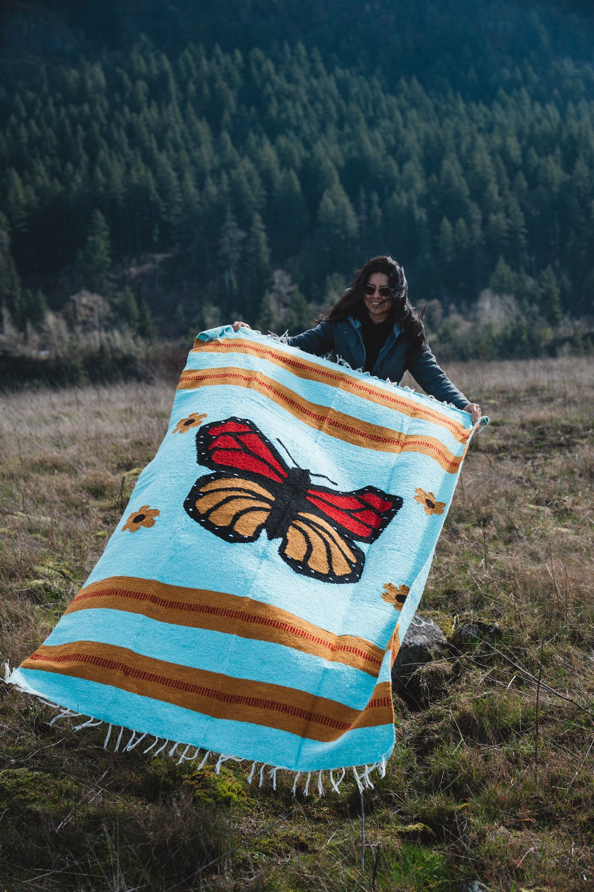 Woman holding monarch butterfly blanket in a field