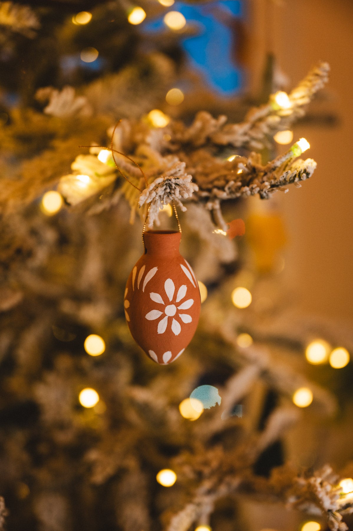 Decorative egg ornament on a Christmas tree with lights in the background