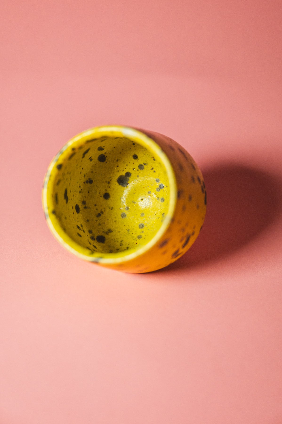 Yellow ceramic cup with textured interior on a pink background