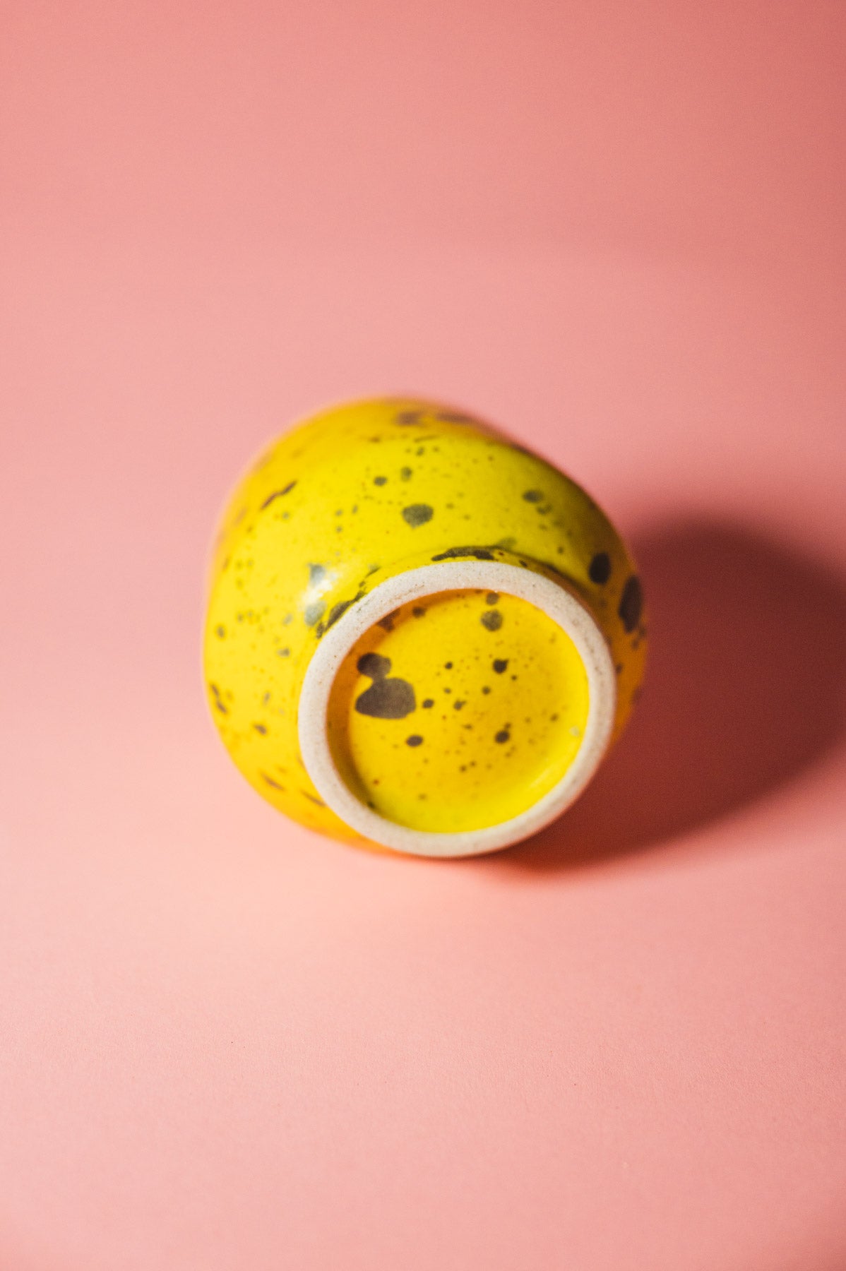 Yellow ceramic jar with speckled pattern on a pink background