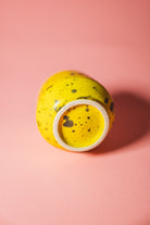 Yellow ceramic jar with speckled pattern on a pink background