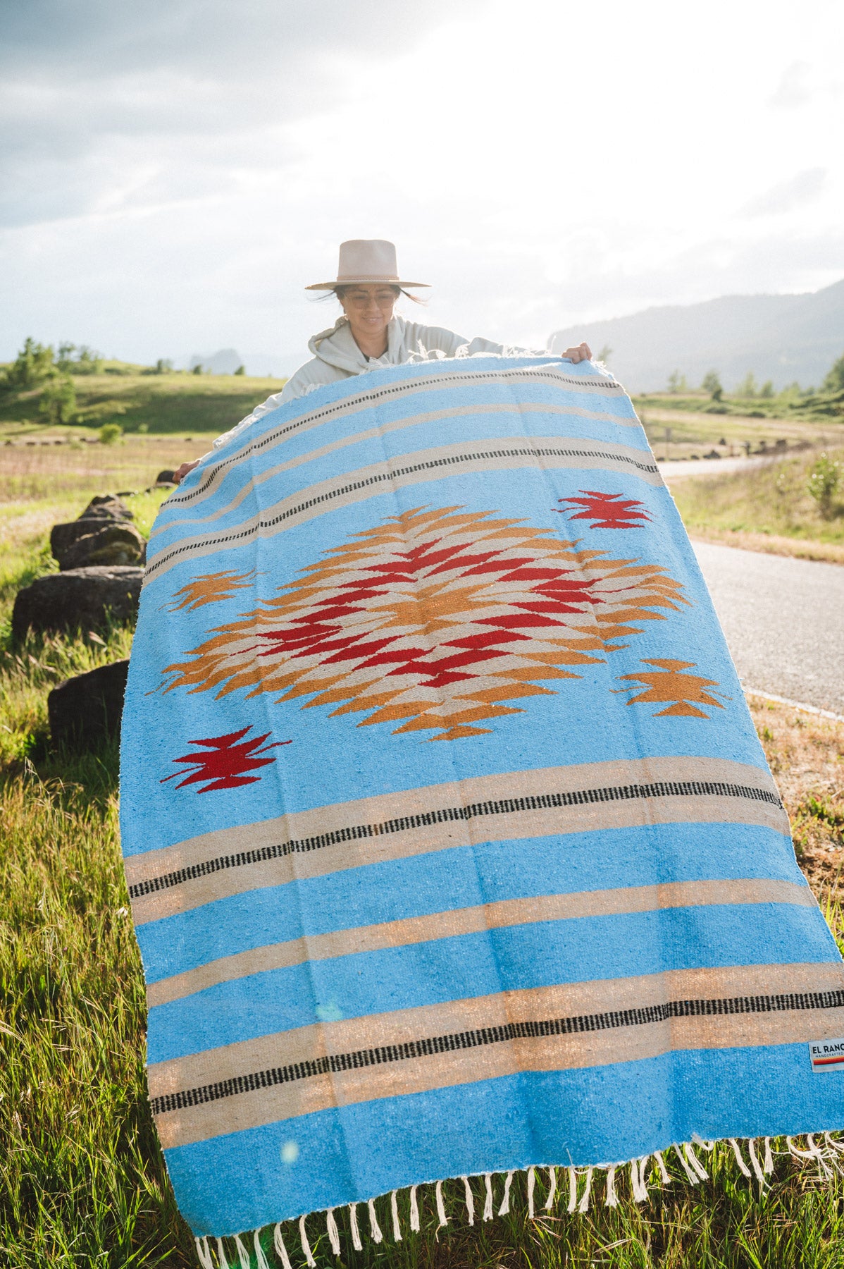 Mexican woman holding a blue handwoven mexican blanket