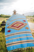 Mexican woman holding a blue handwoven mexican blanket