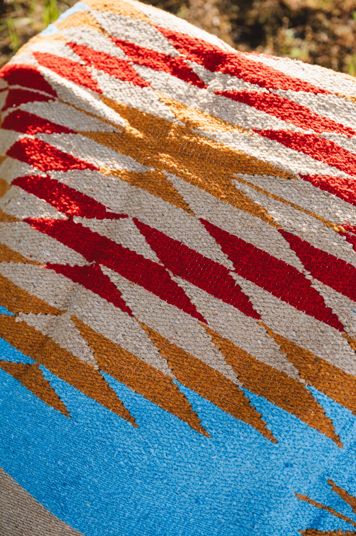 Blue and red mexican diamond blanket laying on the ground