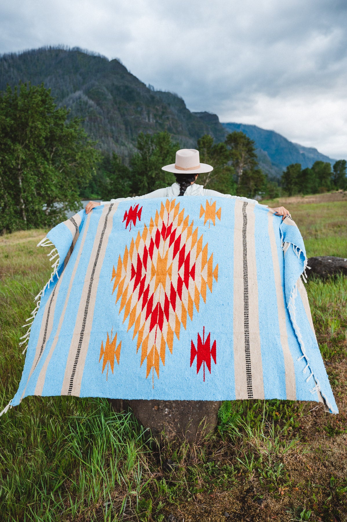 Mexican woman holding a blue handwoven mexican blanket