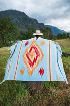 Mexican woman holding a blue handwoven mexican blanket