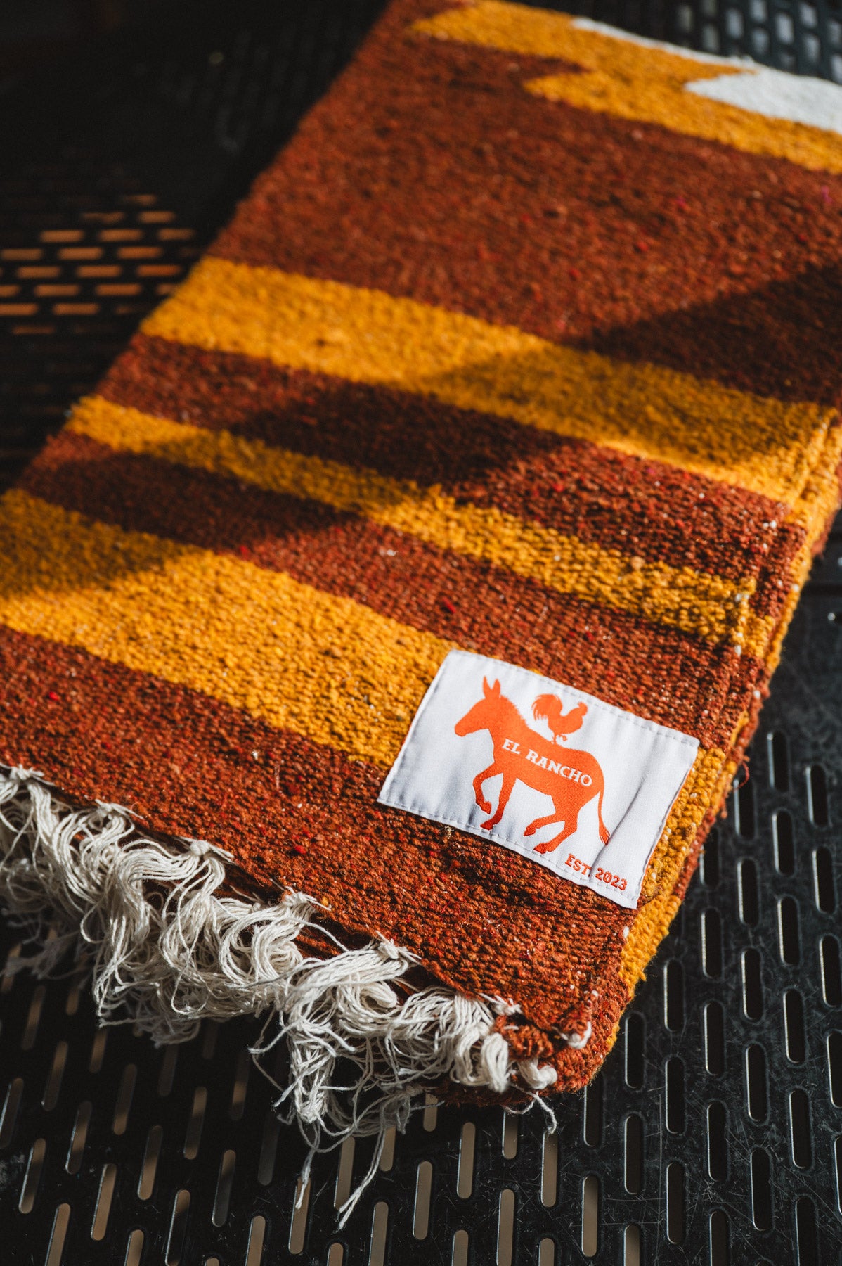 Striped fabric with fringes and a brand label on a textured surface