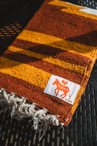 Striped fabric with fringes and a brand label on a textured surface