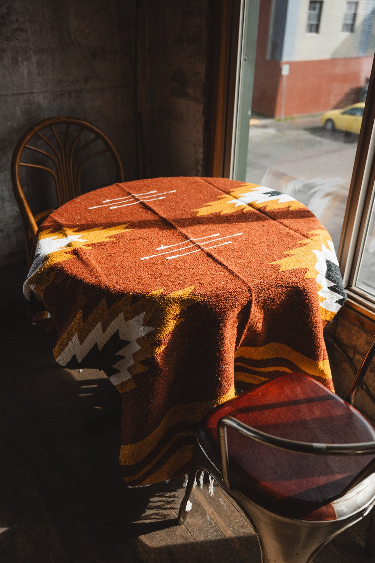 Table with a patterned tablecloth in a window-lined room