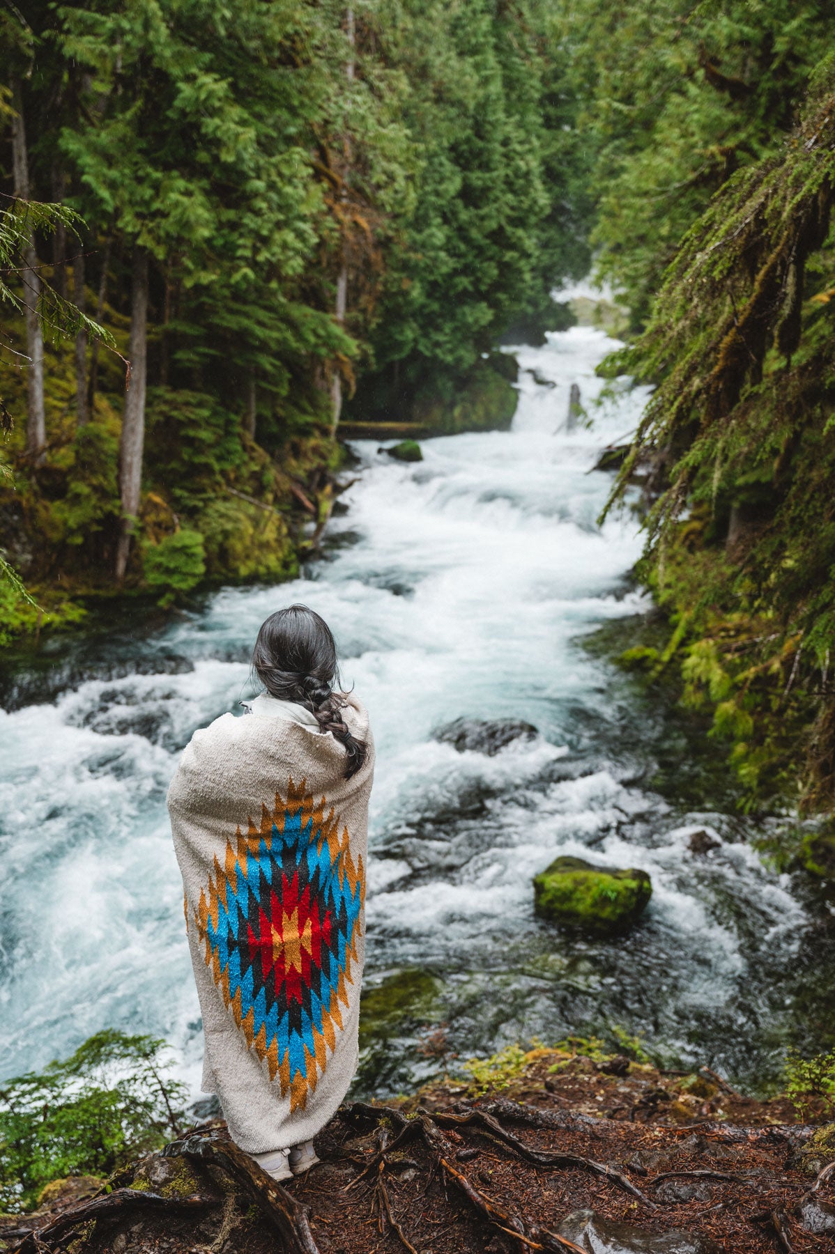 Woman wearing a Handwoven Mexican Blanket in front of Sahalie Falls Oregon in the Mckenzie River Corridor