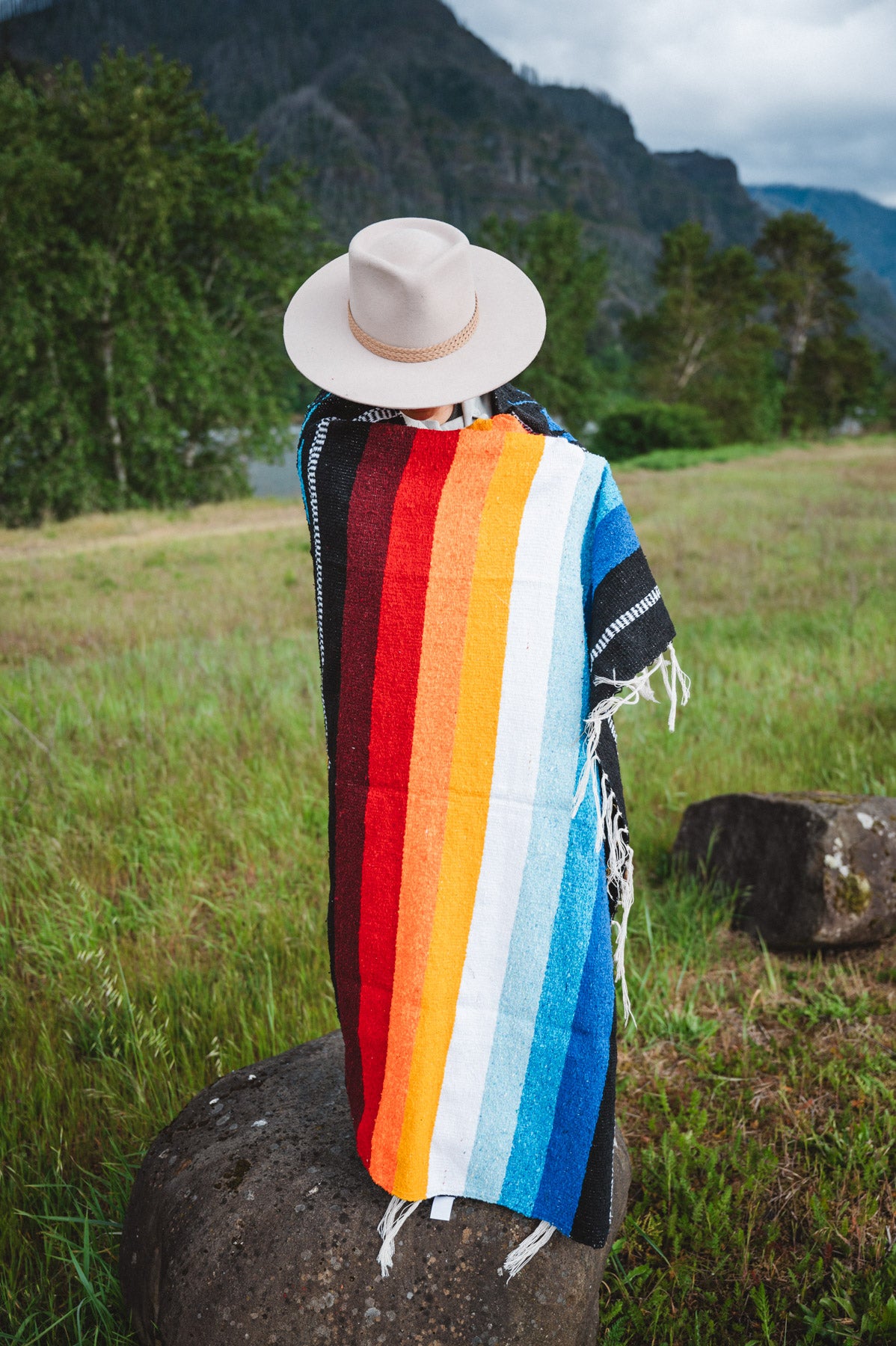 Mexican woman wrapped in a multicolored handwoven mexican blanket with diamond saltillo design