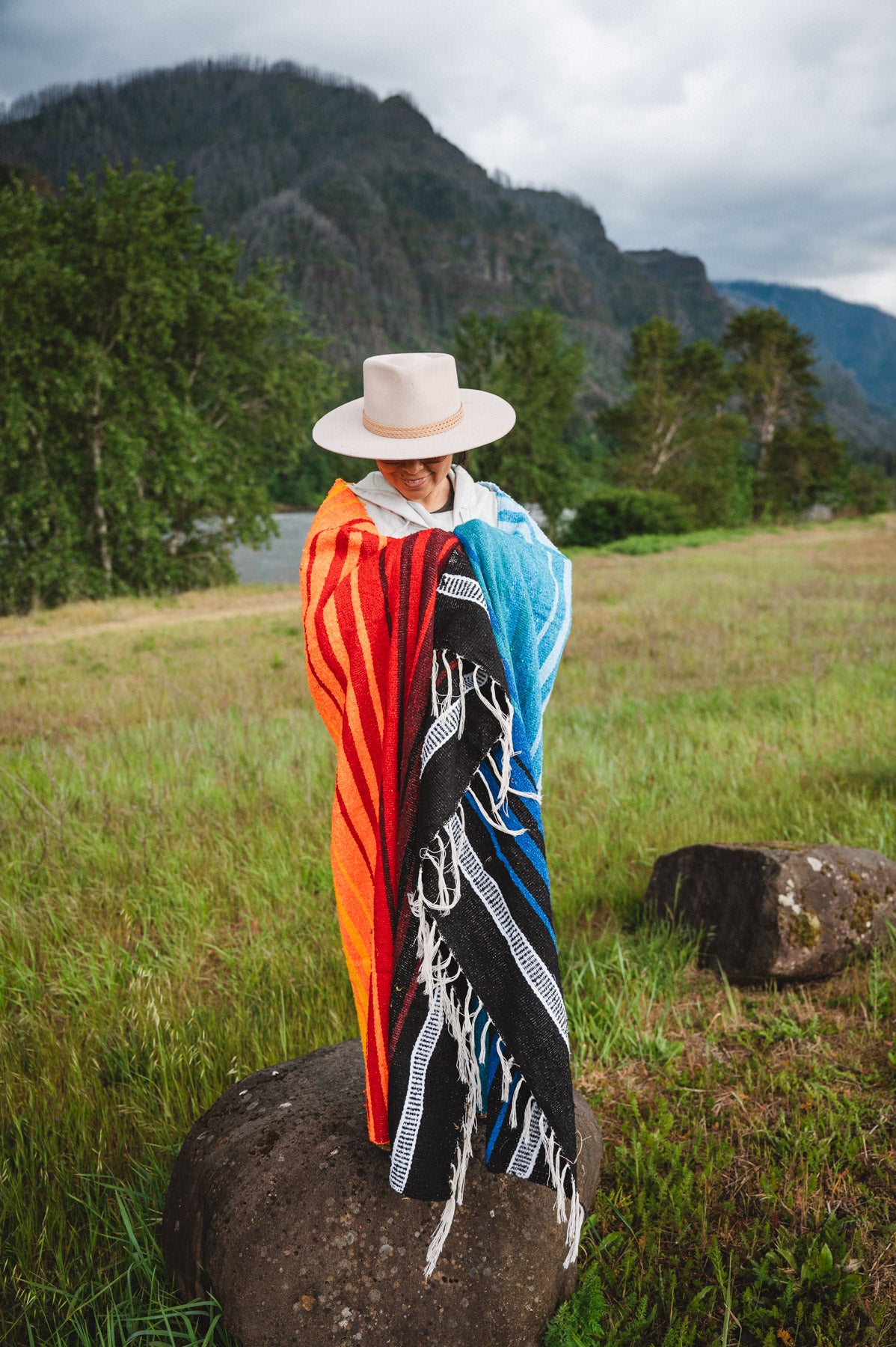 Mexican woman wrapped in a multicolored handwoven mexican blanket with diamond saltillo design