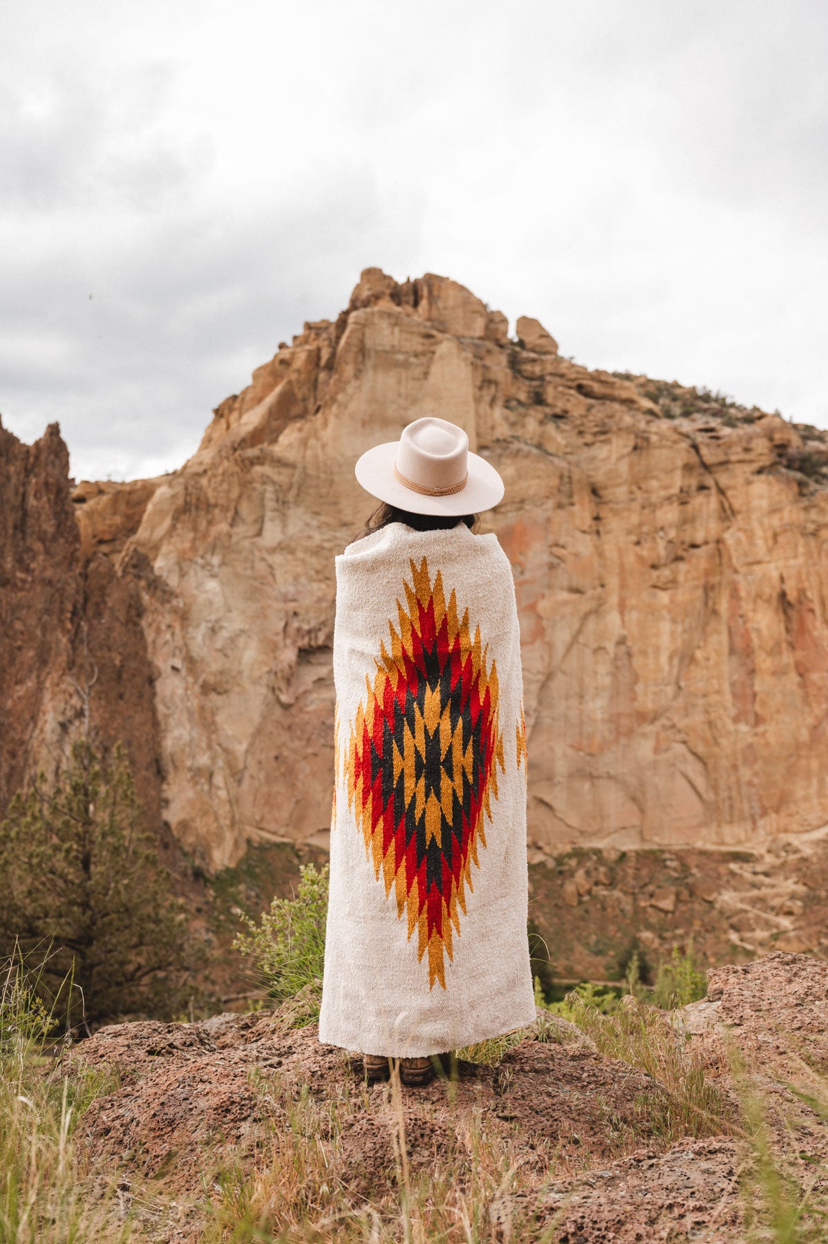 Woman wearing a southwest diamond handwoven blanket at smith rock state park oregon