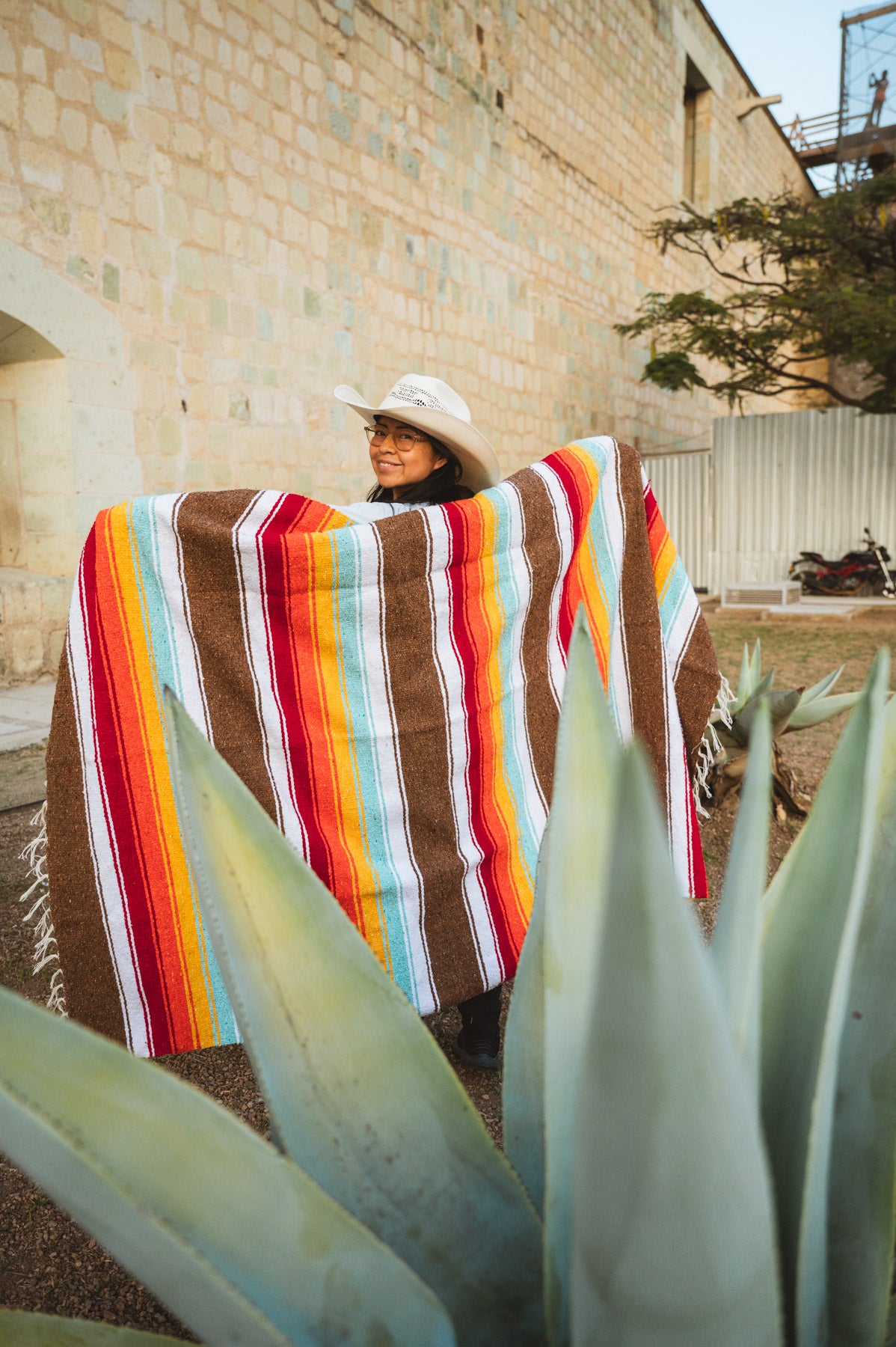 Santo Domingo Church Oaxaca and a girl standing with a handwoven mexican blanket in front of it