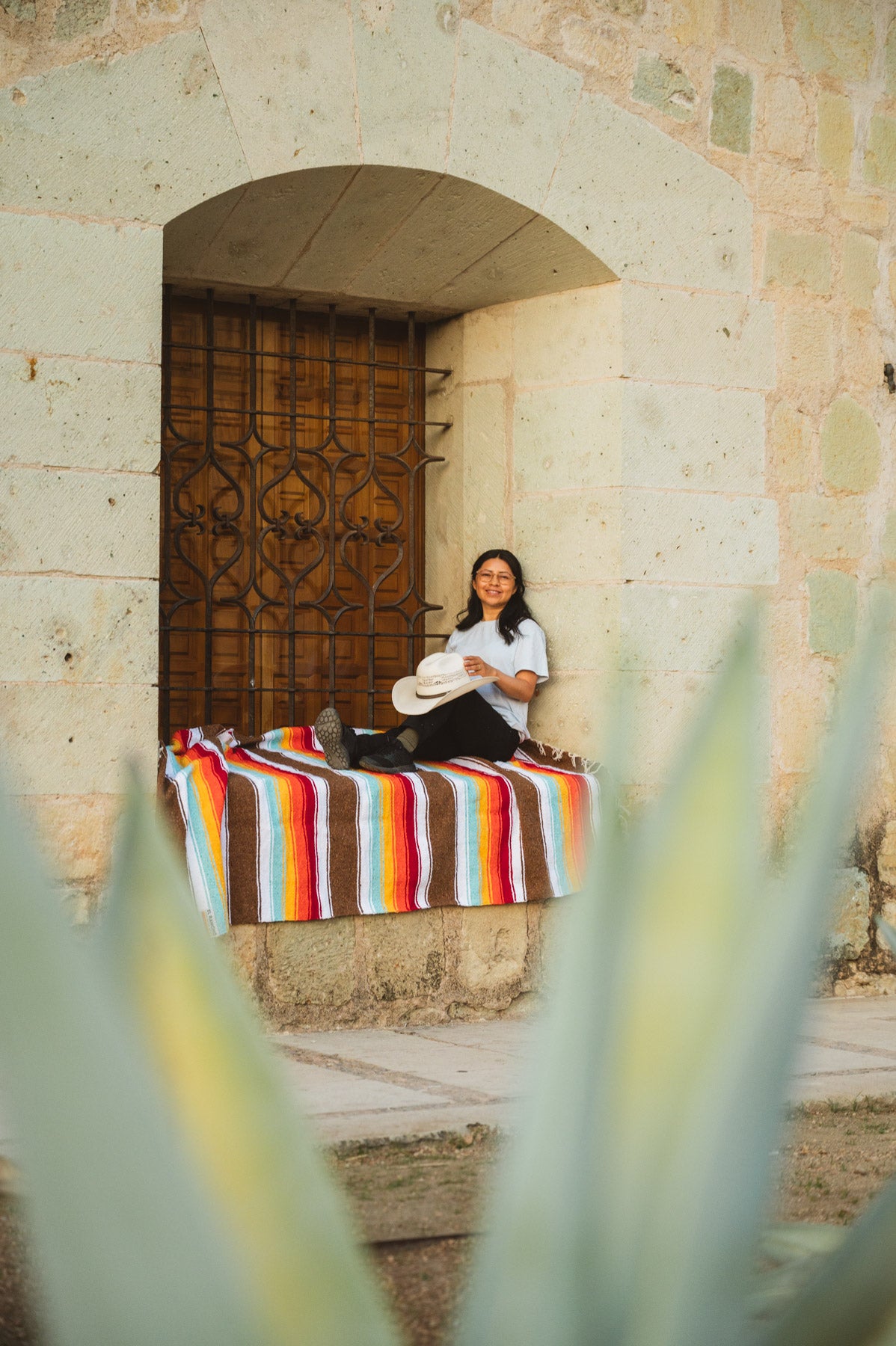 Santo Domingo Church Oaxaca and a girl sitting on a handwoven mexican blanket in front of it