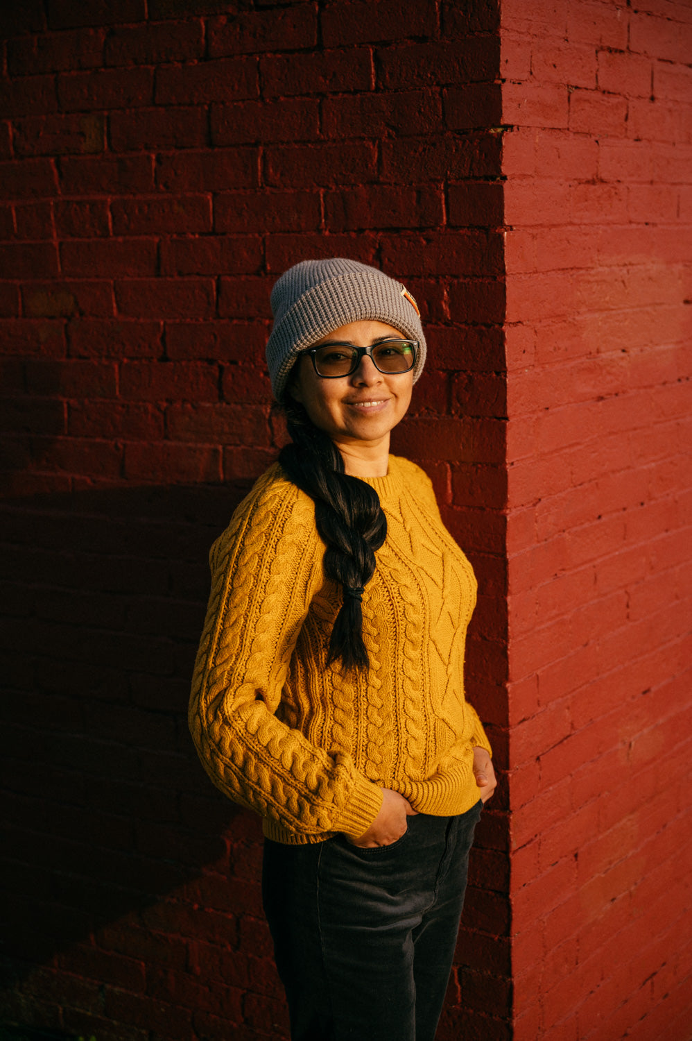 Girl wearing a grey waffle and gold sweater beanie at sunset