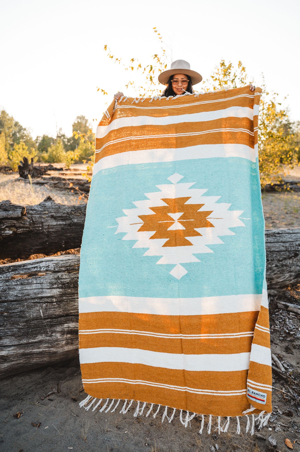 Person holding gold and turquoise handwoven mexican blanket